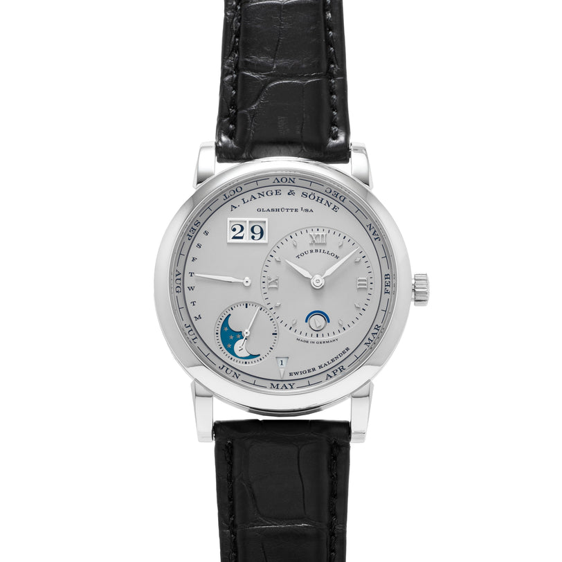 The Lange & Sohne Lange 1 Tourbillon Perpetual Calendar is a silver luxury wristwatch with a black leather strap, featuring multiple dials plus date and moon phase indicators.