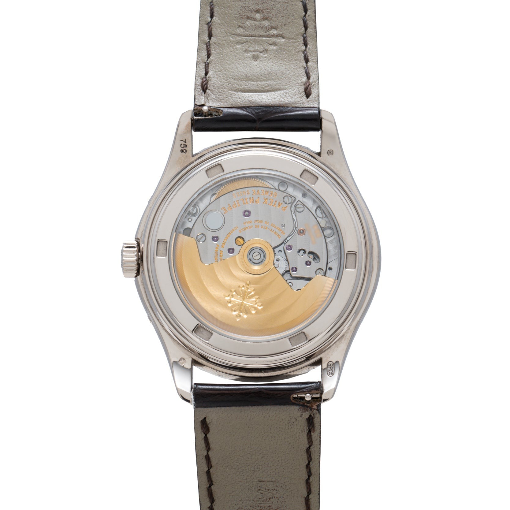 Close-up of Patek Philippe’s Annual Calendar watch, highlighting its transparent case back with an intricate mechanical movement and gold rotor.