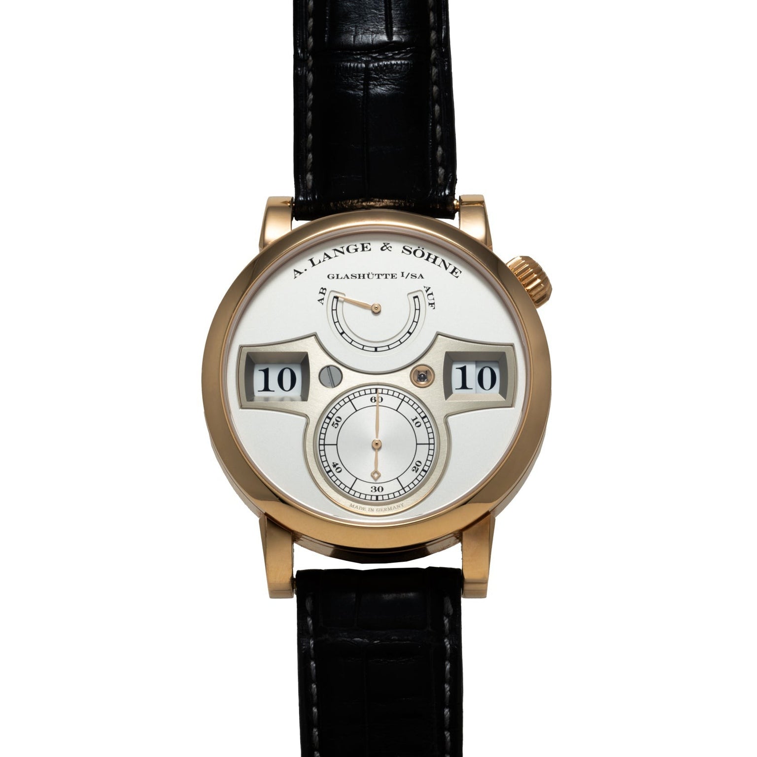 The Lange & Sohne Zeitwerk is a gold wristwatch featuring a white dial with digital hour and minute display and a black leather strap.