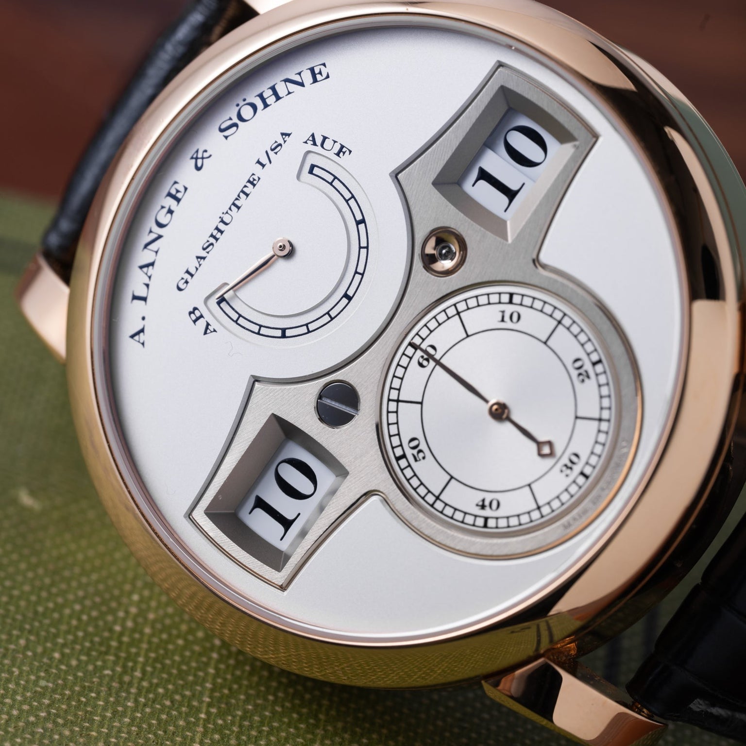 Close-up of a Lange & Sohne Zeitwerk watch featuring a digital hour and minute display with analog seconds.