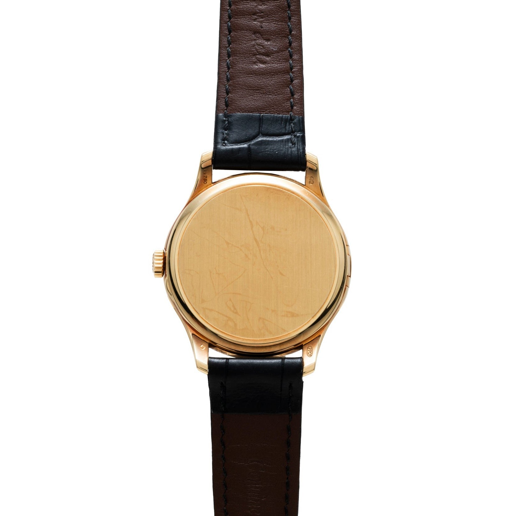 The Patek Philippe Calatrava wristwatch is shown face down, revealing its scratched gold back and the black and brown leather strap.