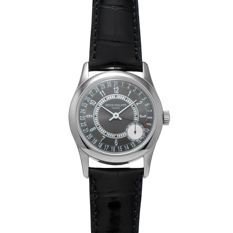 A Patek Philippe Calatrava wristwatch in silver with a black leather strap and a distinctive date dial.