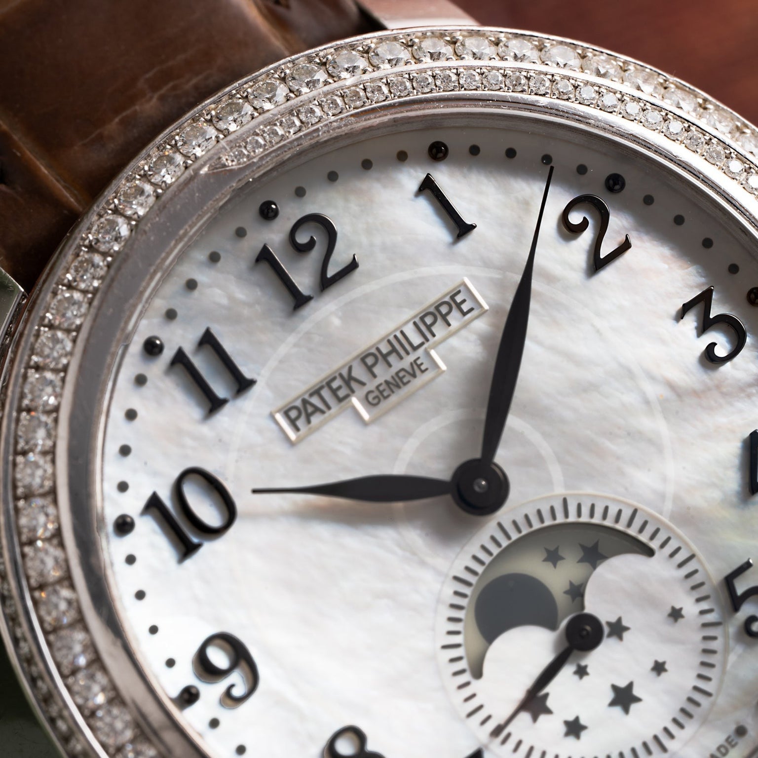 Close-up of the Patek Philippe Ladies Complication watch face, featuring a diamond bezel and moonphase indicator.