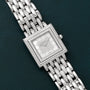 The Patek Philippe Gondolo square wristwatch, adorned with diamonds and a silver metal band, displayed on a dark green background.