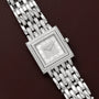 Patek Philippe Gondolo square silver wristwatch with diamond accents displayed on a brown leather surface.