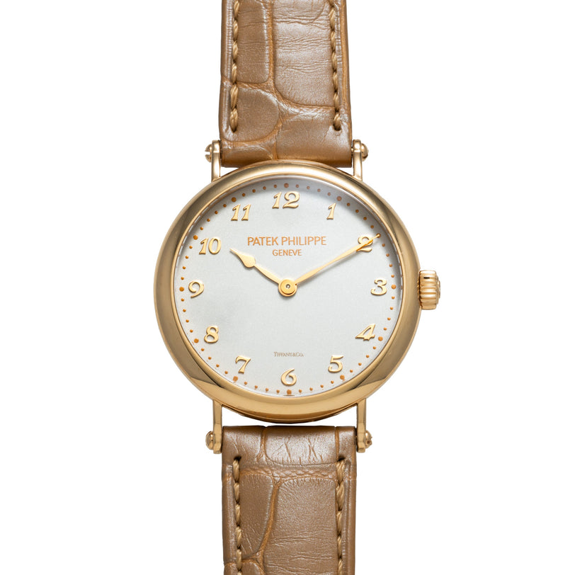 Patek Philippe Calatrava gold wristwatch with brown leather strap and classic numeral dial displayed on a white background.