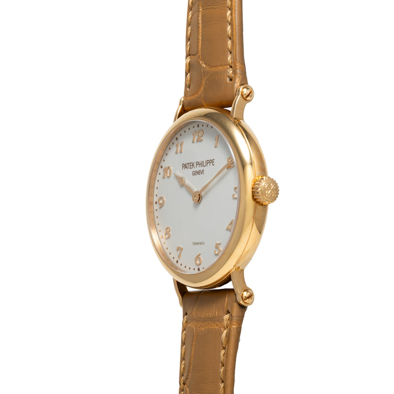 Patek Philippe Calatrava gold wristwatch featuring a brown leather strap and white dial, shown from an angled view.
