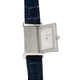 The Jaeger-LeCoultre Reverso Classique Ladies watch features a rectangular silver case, diamond bezel, white dial, and blue leather strap with its signature reversible design partially slid open.