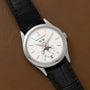 Patek Philippe Annual Calendar Moonphase with black leather strap on brown surface, displays day, date, and moon phase.