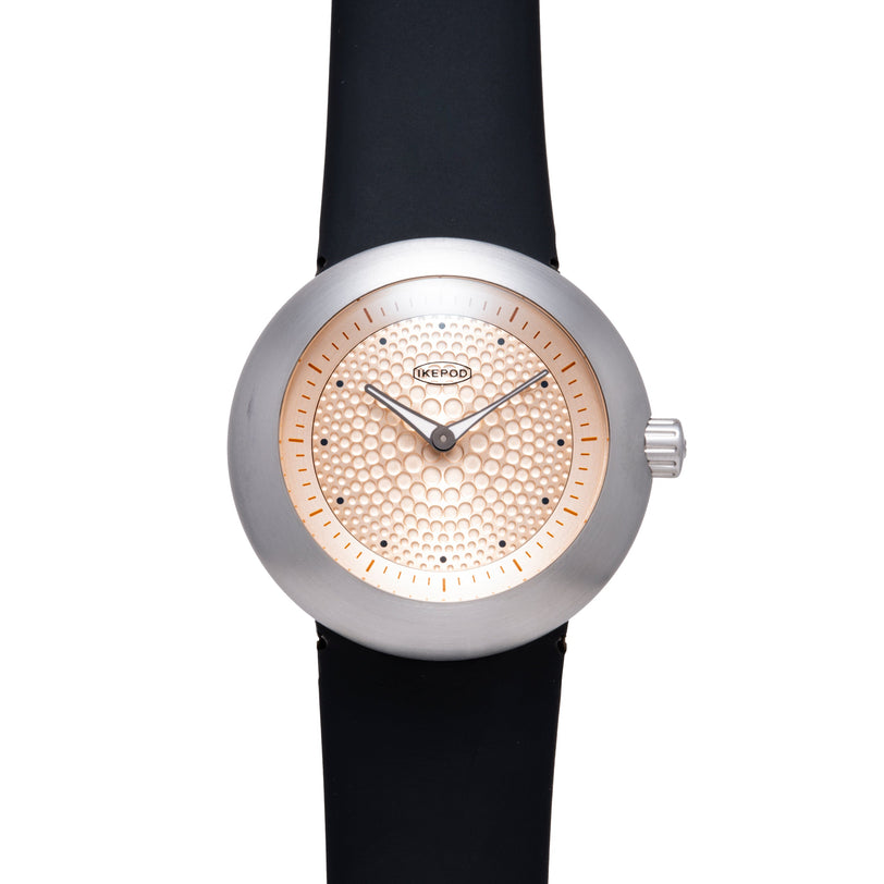 Ikepod Duopod watch with silver case, rose gold dot-patterned dial, black leather strap, and hour markers.