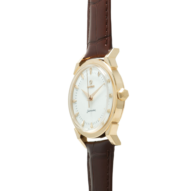 Gold-tone watch with white dial, applied hour markers, and brown leather strap with crocodile texture.