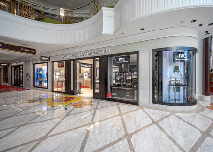 Watch store storefronts with luxury brands in a bright, modern shopping mall with marble floors.