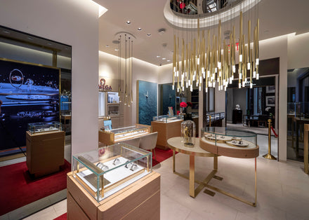 Modern watch boutique with glass display cases, gold light fixtures, and luxury decor.
