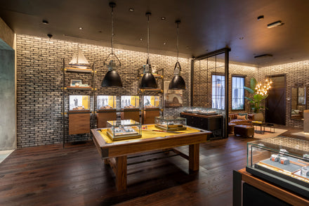 A modern luxury watch store with brick walls, wooden floors, and glass display cases under pendant lights.