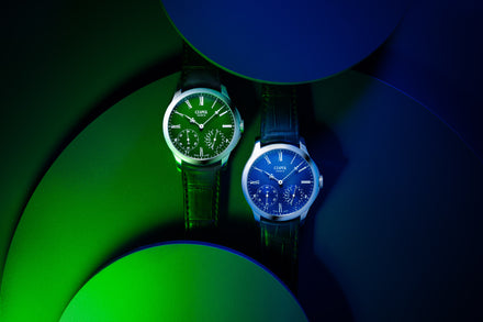 Two Czapek watches, one with a green dial and one with a blue dial, with spotlights of blue and green light