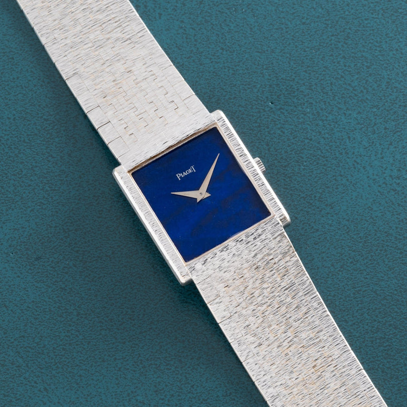 A Piaget White Gold Lapis Lazuli Dress Watch with a blue face and textured metal band, shown on a teal background.