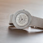 An Audemars Piguet Signed Disco Volante Dress Watch Gübelin with a mesh band rests on a wooden surface.