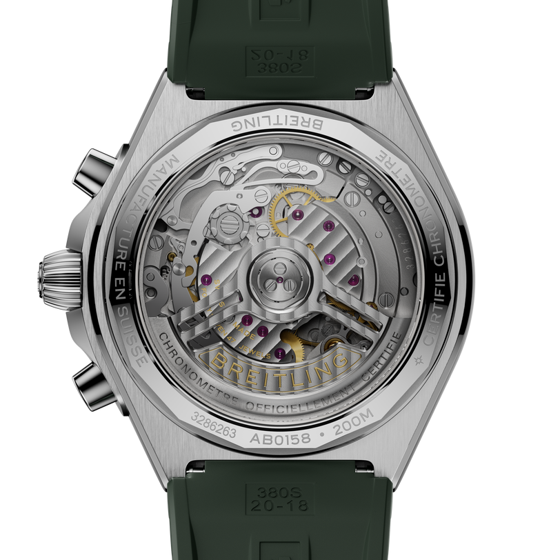 Stainless steel watch with visible mechanical movement through transparent caseback, green rubber strap, and chronograph push