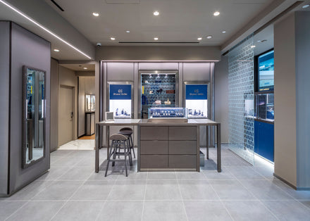 Modern jewelry store interior with display cases, stools, and blue accent walls.