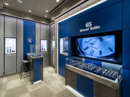 A modern Grand Seiko watch boutique with blue displays, watches in glass cases, and branded signage.