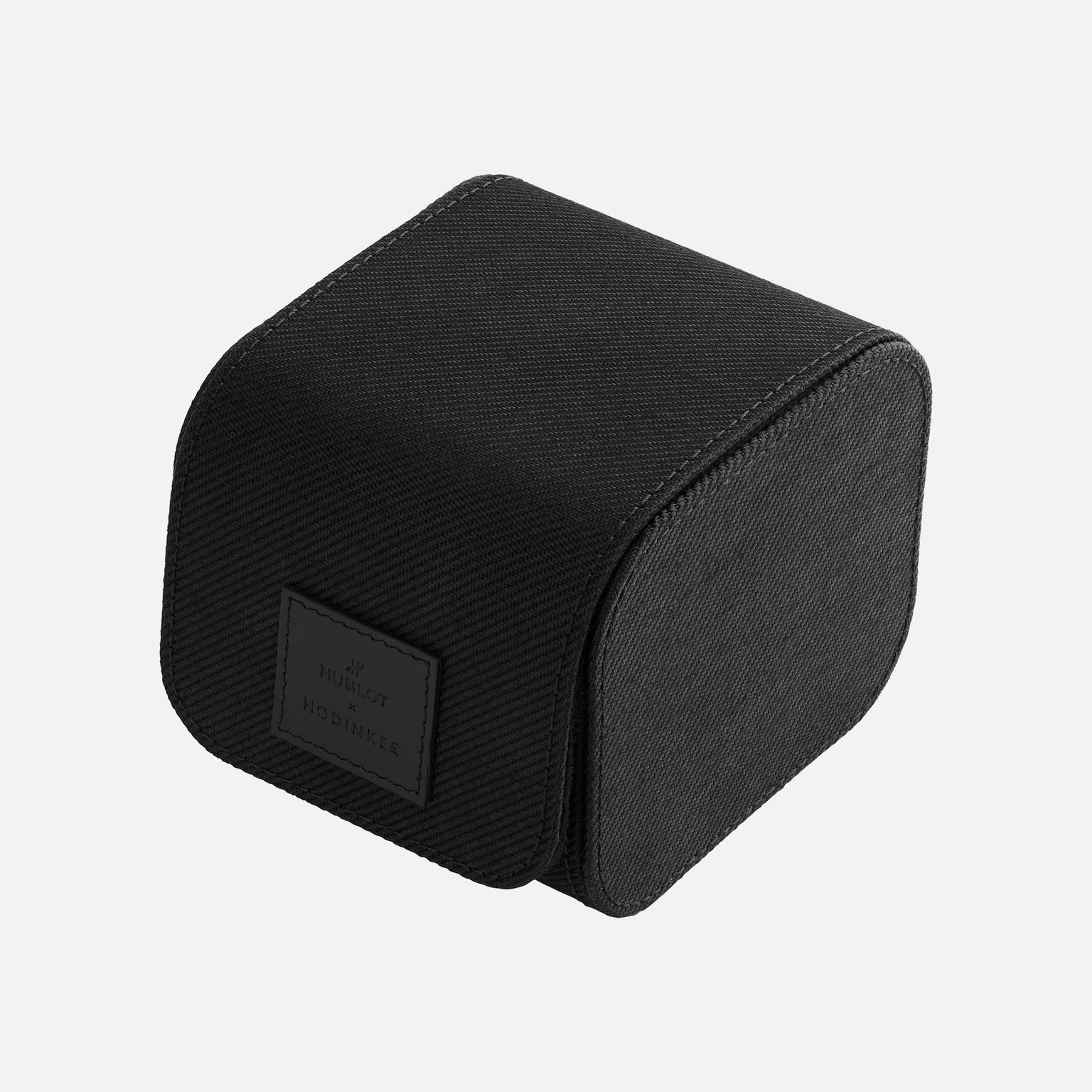 Sleek black rectangular fabric-covered watch box with curved front and “Hublot Boutique” label, designed for the Hublot Classic Fusion Titanium Limited Edition For Hodinkee. Shown against a plain white background.