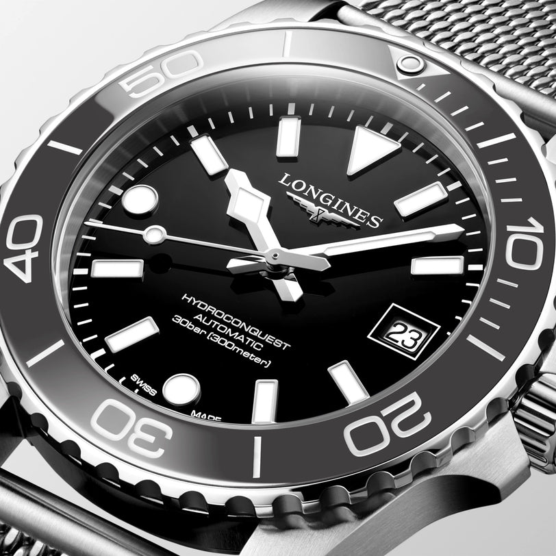 Longines watch with black dial and silver metal bracelet on a light gray background