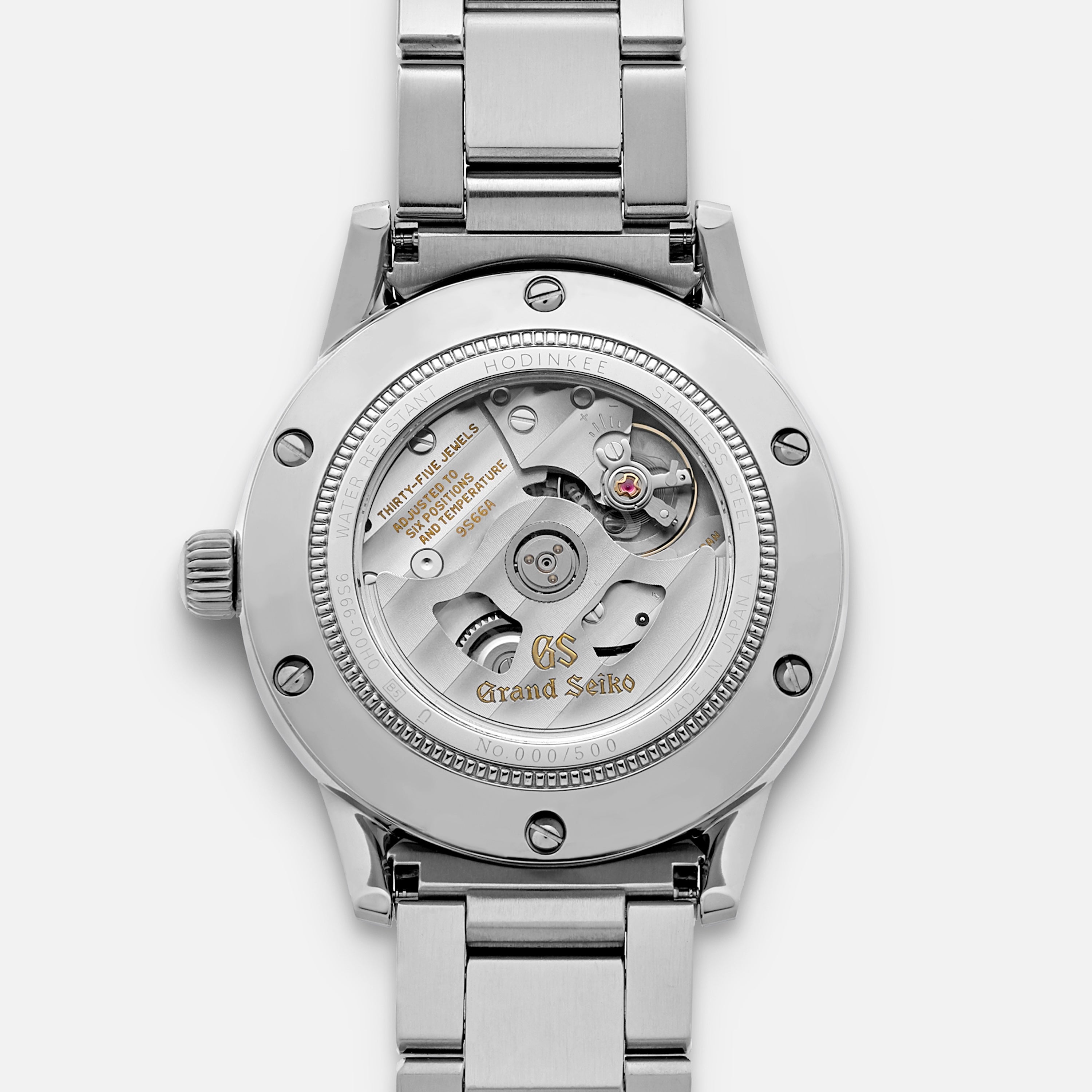 Close-up of the Grand Seiko Automatic GMT SBGM239 Limited Edition for HODINKEE shows its exposed mechanical movement, engraved details, and stainless steel bracelet—highlighting a masterpiece from Grand Seiko.