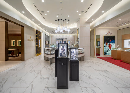 Luxury watch store interior with bright lighting, showcasing Rolex and Omega displays and modern decor.
