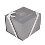 A gray gift box with white ribbon and gold and white text, branded by TAG Heuer—ideal for celebrating the Connected Calibre E4 Golf Edition or presenting an ultra-light titanium timepiece.