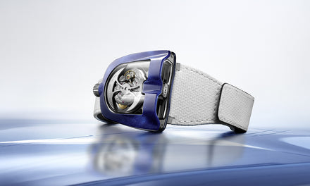 A futuristic blue and silver wristwatch with a white strap displayed on a blue and white surface.