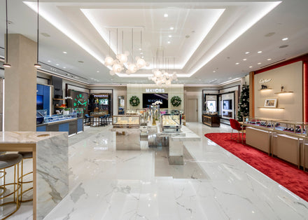 A bright, modern jewelry store with glass display cases, marble floors, and elegant lighting fixtures.