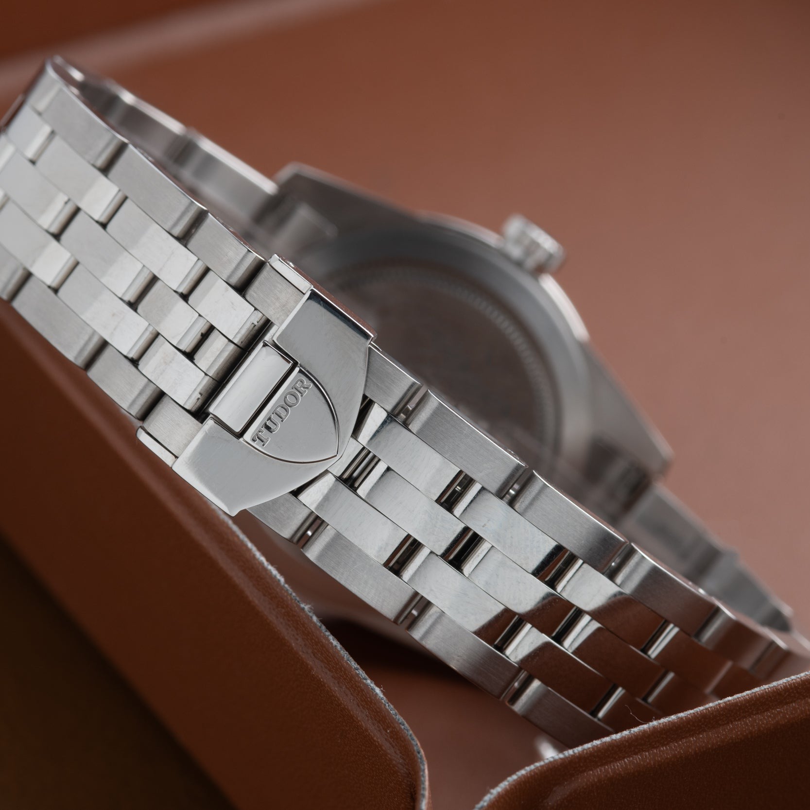 Close-up of a TUDOR Glamour Date silver bracelet and clasp resting on a brown leather surface.