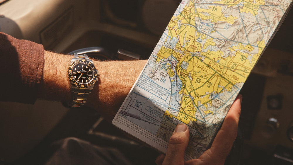 Two hands hold a road map of San Diego, the left wrist wears a Rolex GMT Master II