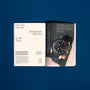 An open HODINKEE Magazine, Volume 12 by Hodinkee sits on a blue surface, showing the article Our Ten Favorite Moonphase Watches of All Time, with a large wristwatch photo and references to classic watch ads.