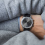 A person in a gray sweater is showcasing a Zenith El Primero Limited Edition For Hodinkee wristwatch with a black leather strap and gray dial on their wrist.