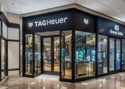 TAG Heuer watch boutique with glass doors and display cases in a shopping mall, next to Grand Seiko store.