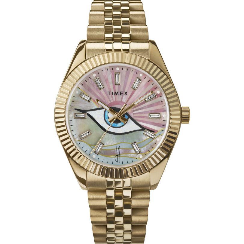 The Timex x Jacquie Aiche watch by Timex features a gold-tone metal link band, a pink iridescent mother-of-pearl dial with an eye motif at the center, and rectangular hour markers.