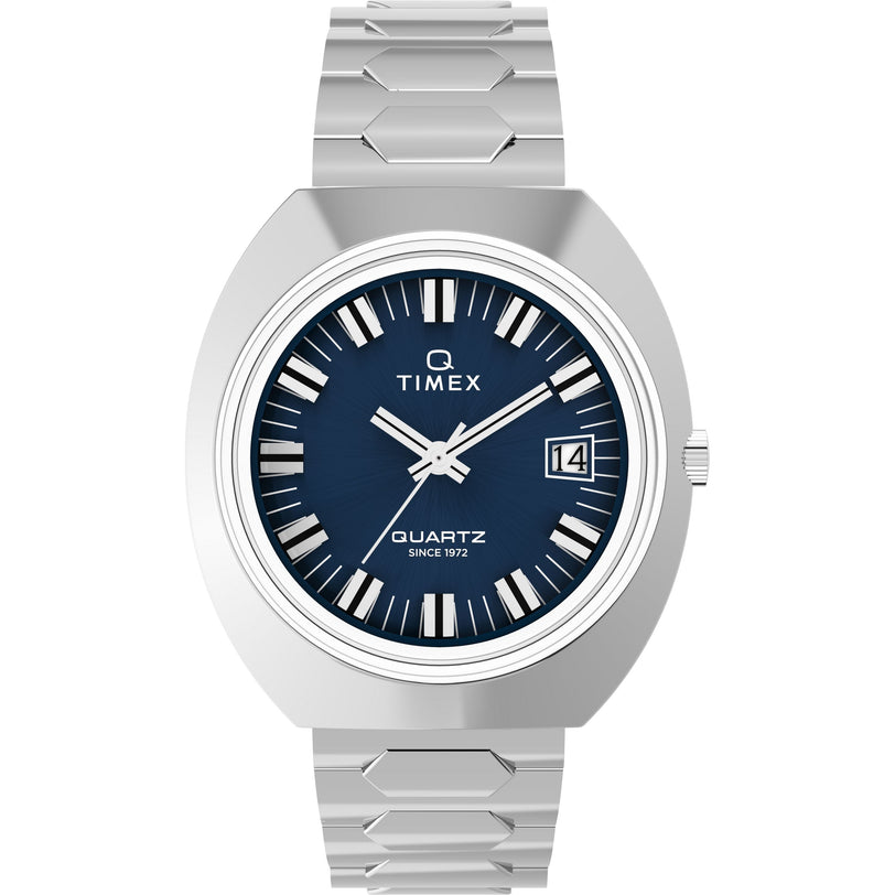 The Timex Q 1972 Time Machine Reissue is a silver watch with a blue face, bold white hour markers, silver hands, date window at 3 o’clock, geometric bracelet, archival quartz movement, and "Quartz Since 1972" on the dial.