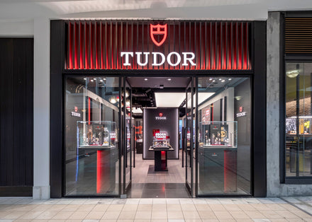 TUDOR watch store with illuminated sign, glass display cases, and modern interior in a shopping mall.