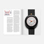 The left page of Hodinkee Magazine, Volume 14 features text, while the right displays a black round leather-strap wristwatch from Hodinkee.