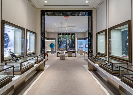 Luxury watch store interior with glass display cases and elegant lighting showcasing various watches.