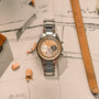 The Zenith Chronomaster Original Limited Edition For Hodinkee, featuring a cream and tan dial, rests on sketches with wooden pencils and shavings—a tribute to classic design.