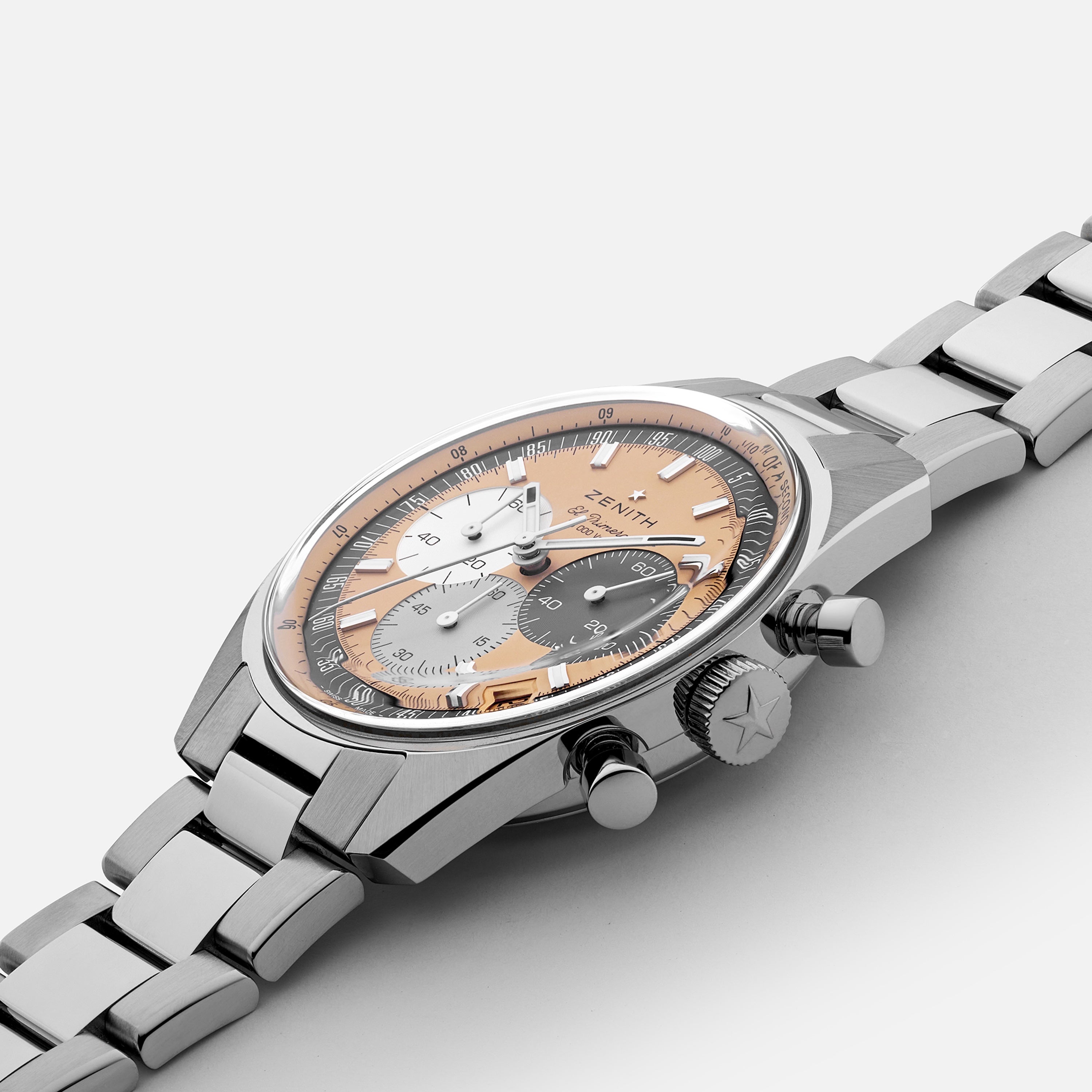 A Zenith Chronomaster Original Limited Edition for Hodinkee wristwatch features a stainless steel case, silver, black, and gold tri-color El Primero dial, and metal bracelet, shown on a white background.