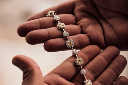 Two hands hold a jeweled bracelet with many small yellow and white stones