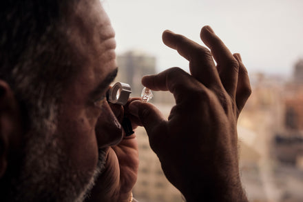 A person holds a cut stone up to a magnifying glass