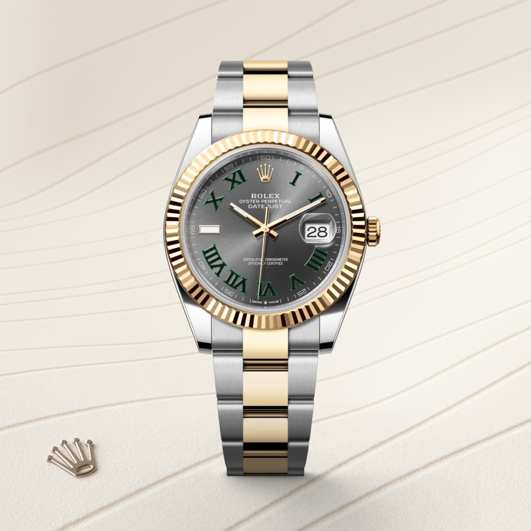 A two-tone Rolex watch with a gray dial, green Roman numerals, and a date window on a patterned background.