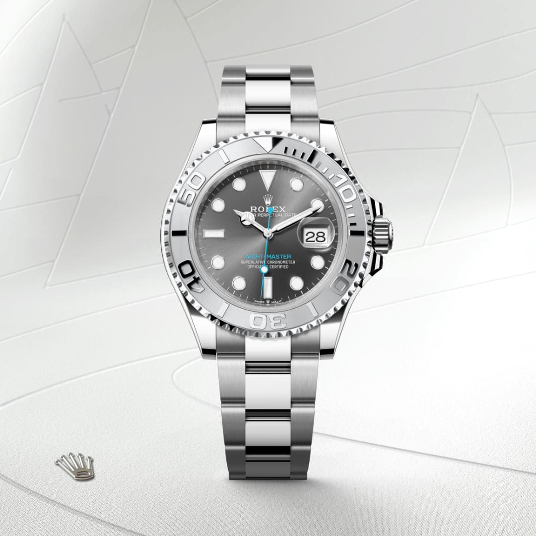 A silver Rolex Yacht-Master watch with a grey dial and date display, shown on a light, textured background.