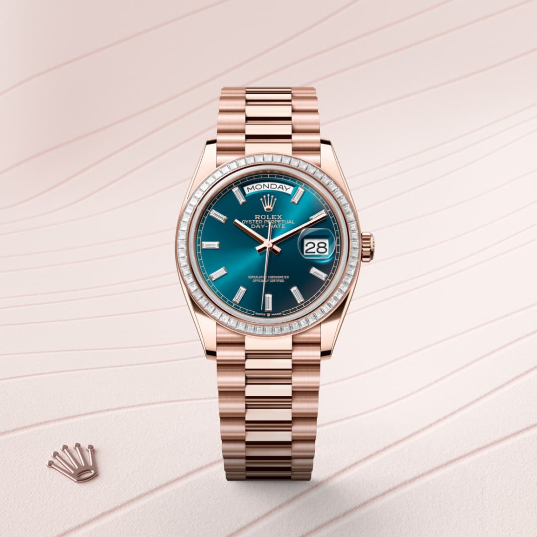 A rose gold Rolex watch with a teal face and diamond bezel, displayed on a pale textured surface.