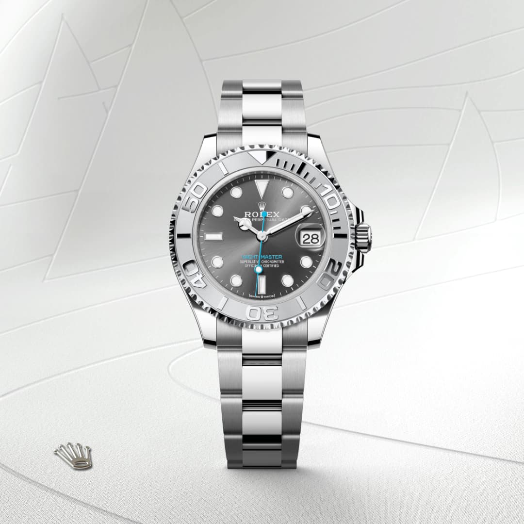 Silver Rolex Yacht-Master watch with a grey dial and date display, set against a light textured background.