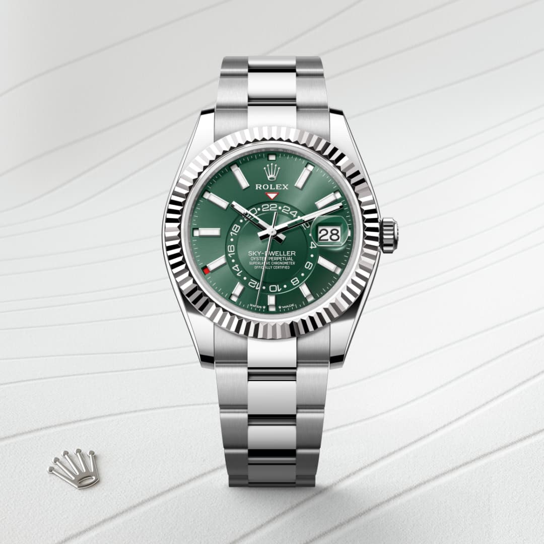 A silver Rolex Sky-Dweller watch with a green dial and date display on a white textured background.